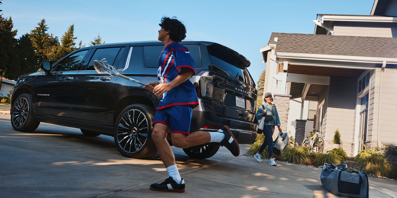 A Young Lacrosse Player Running to the 2026 Chevy Suburban Followed by His Mom Outside of Their Home