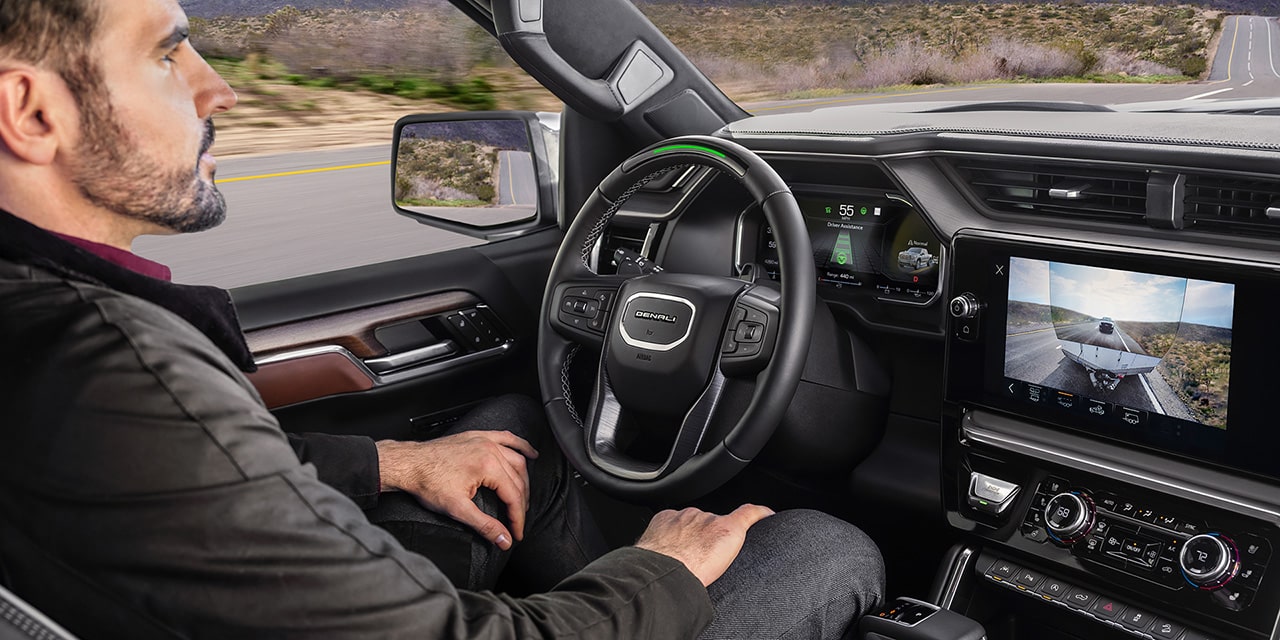 Profile View of a Man Driving the 2026 GMC Sierra Denali Luxury Pickup Truck Using the Super Cruise Hands-Free Driving Technology